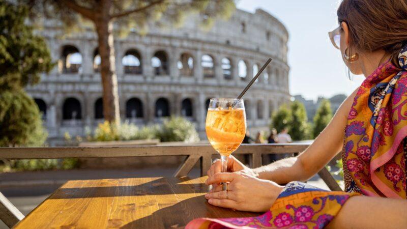A woman drinking aperol spritz near the Colloseum