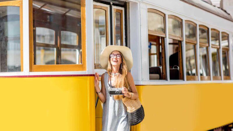 A woman is staying next to the famous yellow tram in Lisbon