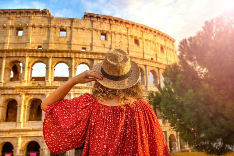 A woman in a red dress next to Colloseum, enjoying her private tour to Italy