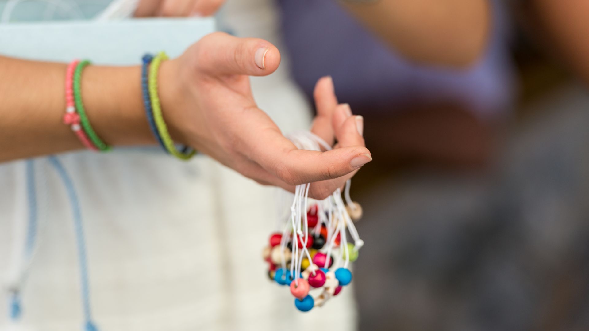 A close-up of a hand holding hand-made bracelets