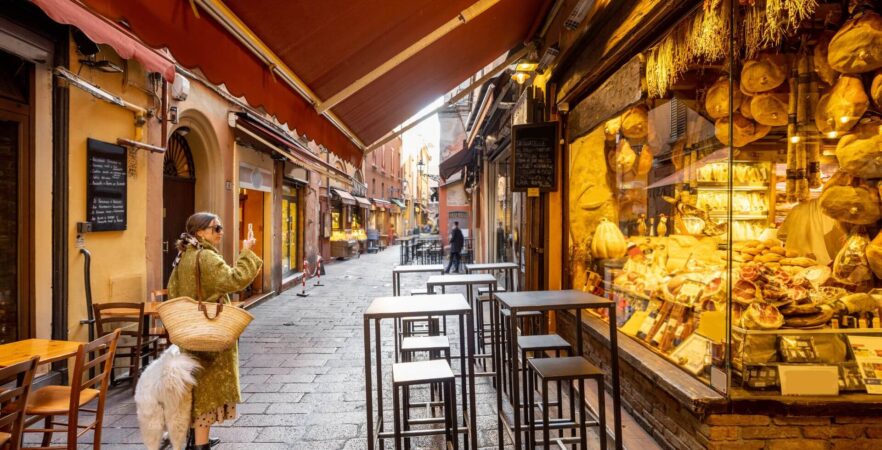 A woman near a food store in Bologna, a must-visit destination on a food tour to Italy