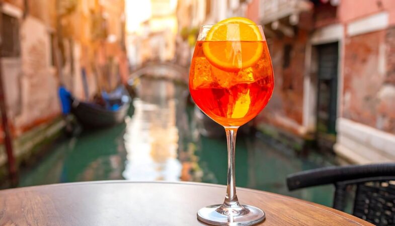 Glass of Aperol Spritz on a table in a cafe overlooking the Venice canals, a "must" experience during an Italy tour